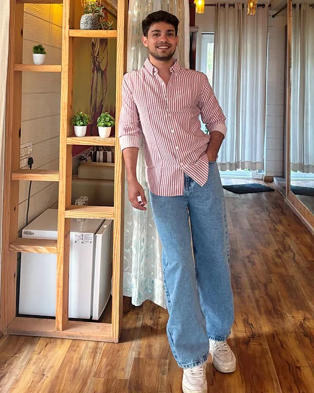 Aman in a striped shirt in a wooden room